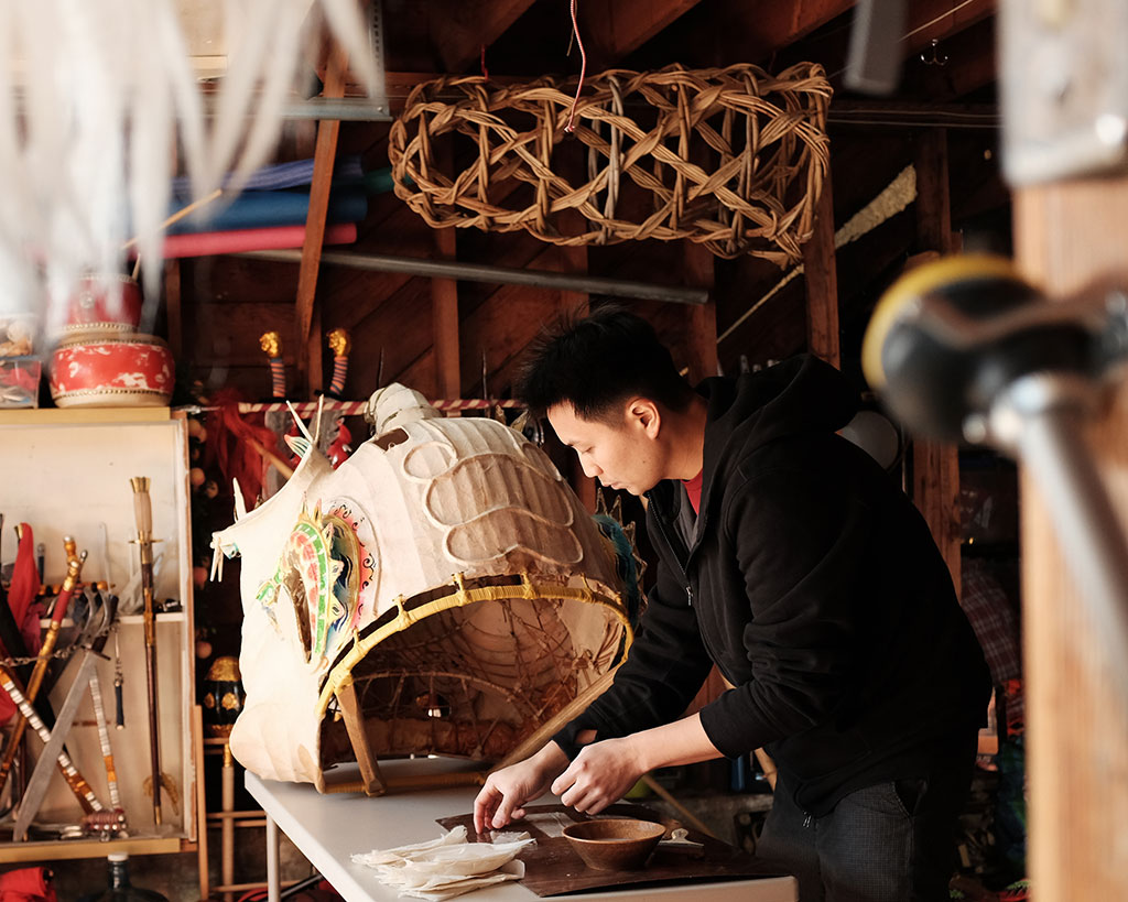 Travis Lum delicately repairs a lion head. Mark Markley photograph, CELEBRATION episode, Craft in America