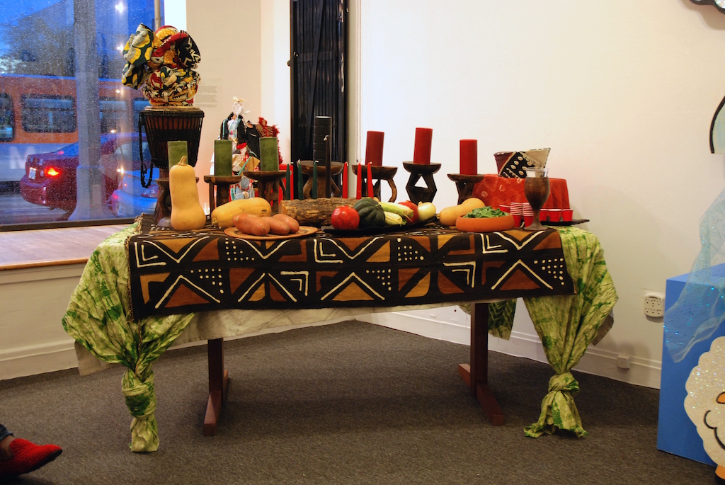 The Kwanzaa table is set at the Craft in America Center. On both ends of the table sit traditional hats created by LA's Hatzy Lady, Yvonne Lewis.