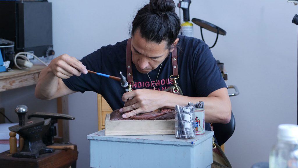 Artist Nicholas Galanin chasing a copper mask. Craft in America STORYTELLERS