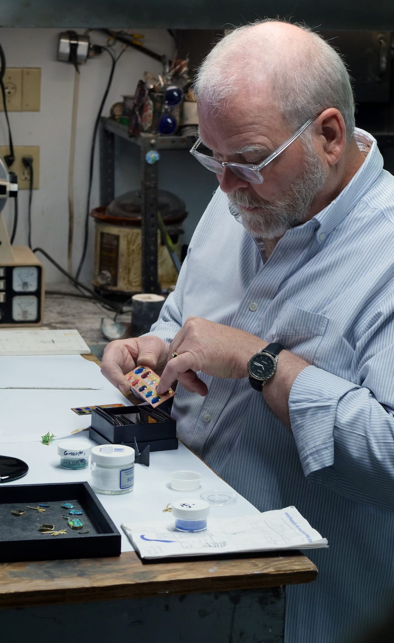 Tom Herman shows enamel samples. Denise Kang photo. JEWELRY episode of Craft in America