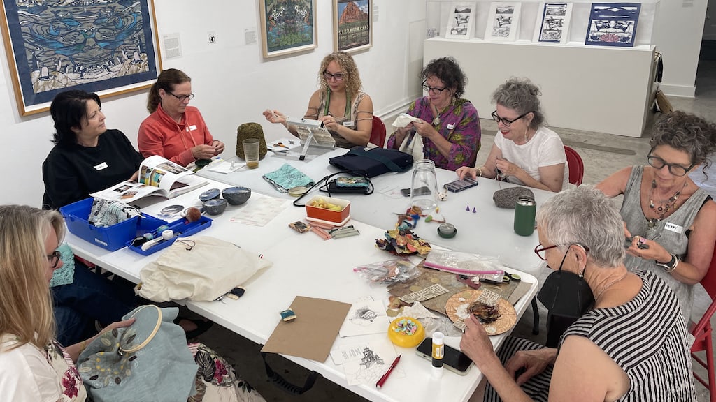 Group of people around a table working on crafts at the Craft in America center
