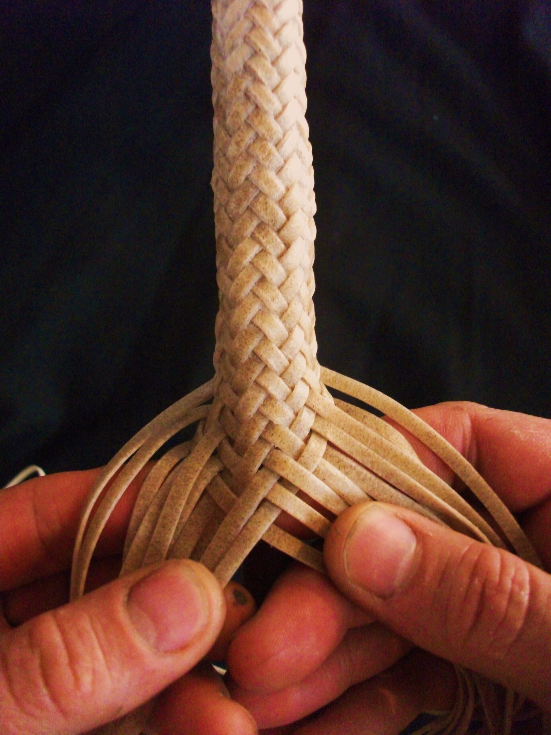 Photo of Pablo Lozano's hands as he braids a strand of rawhide