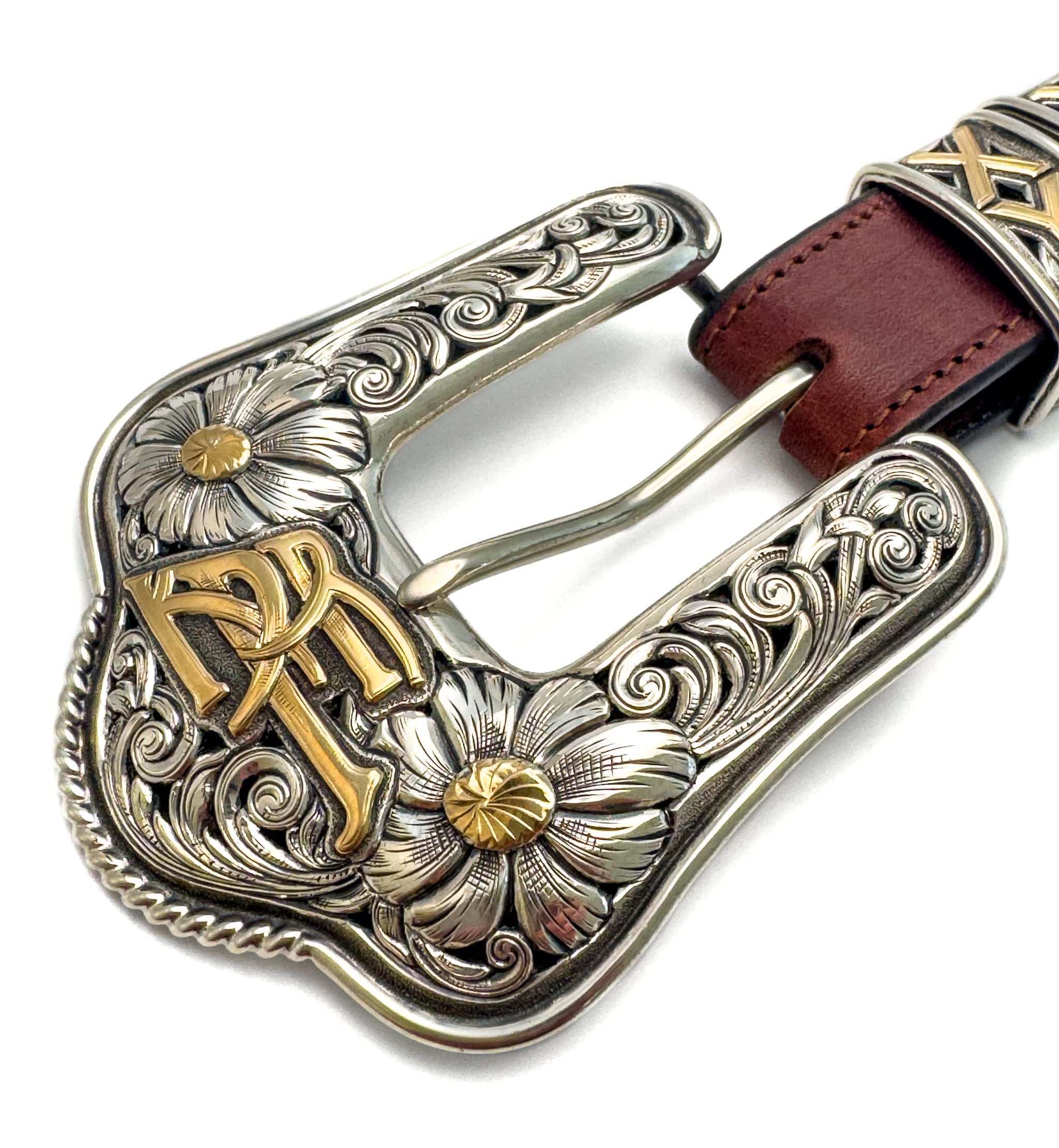 Close up of an ornate silver and gold engraved belt buckle