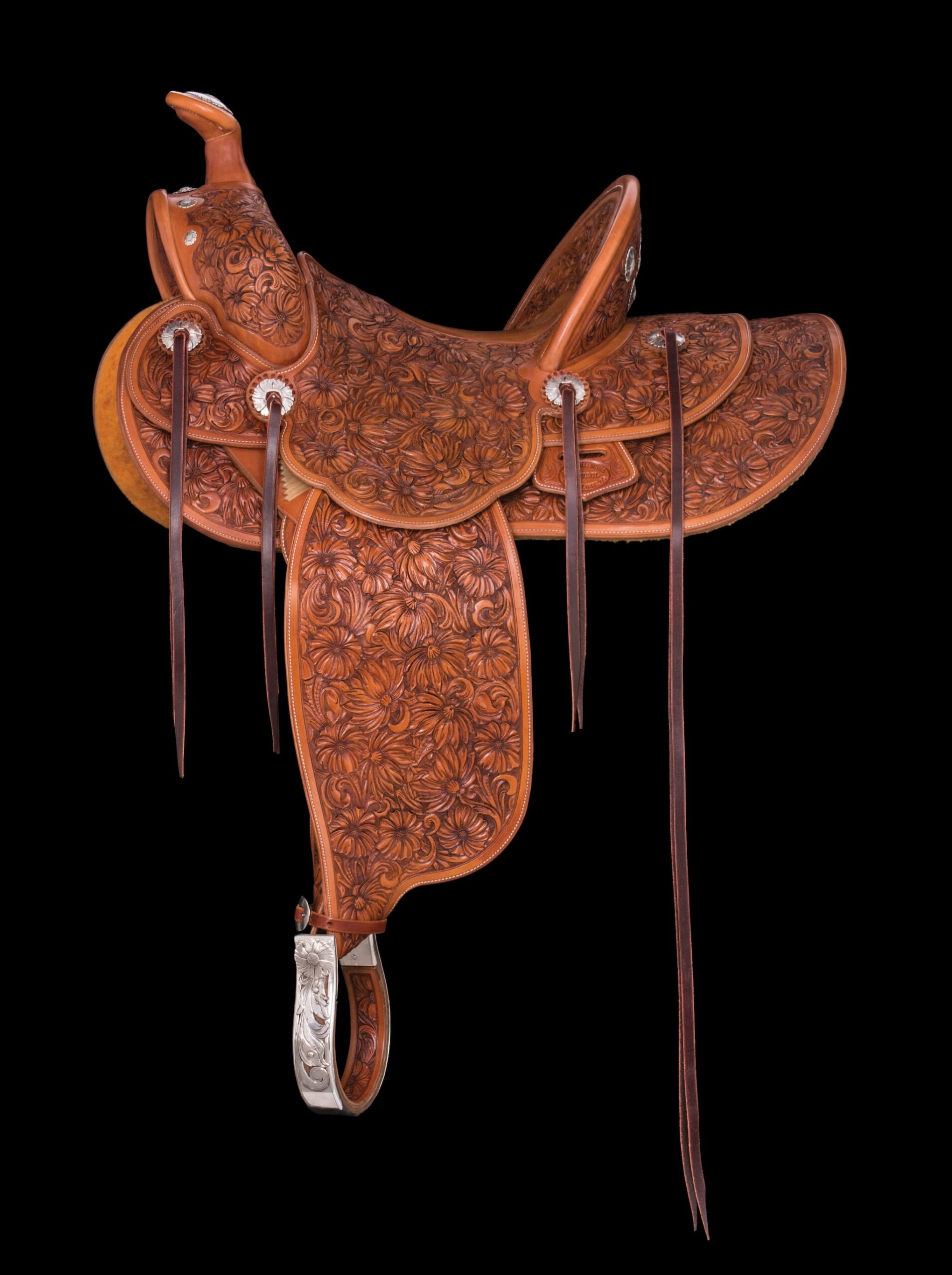 A brown leather saddle, hand-engraved with a floral pattern and accented with with engraved silver details