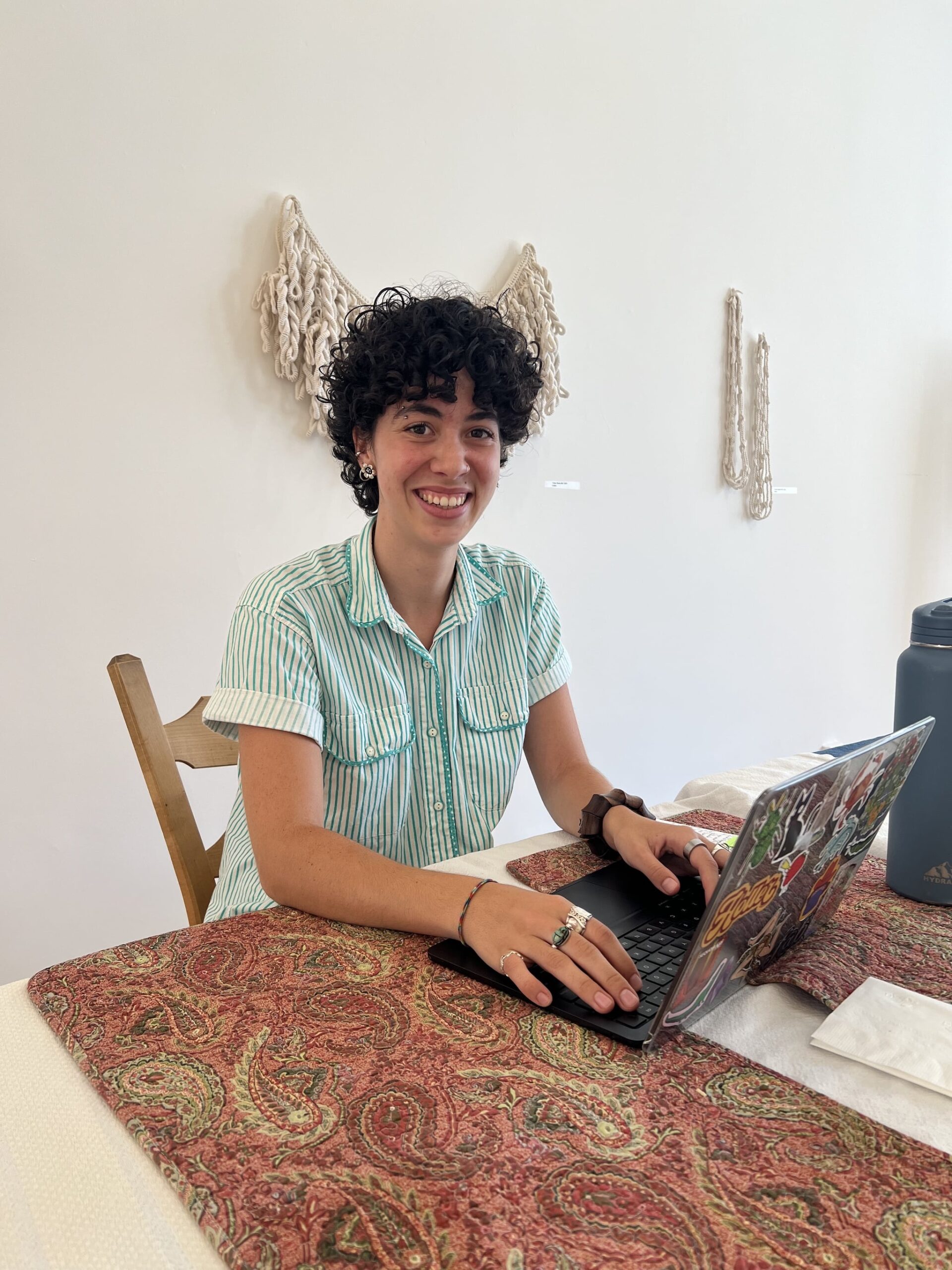 Ellanora sitting at a table at the Center typing on her computer